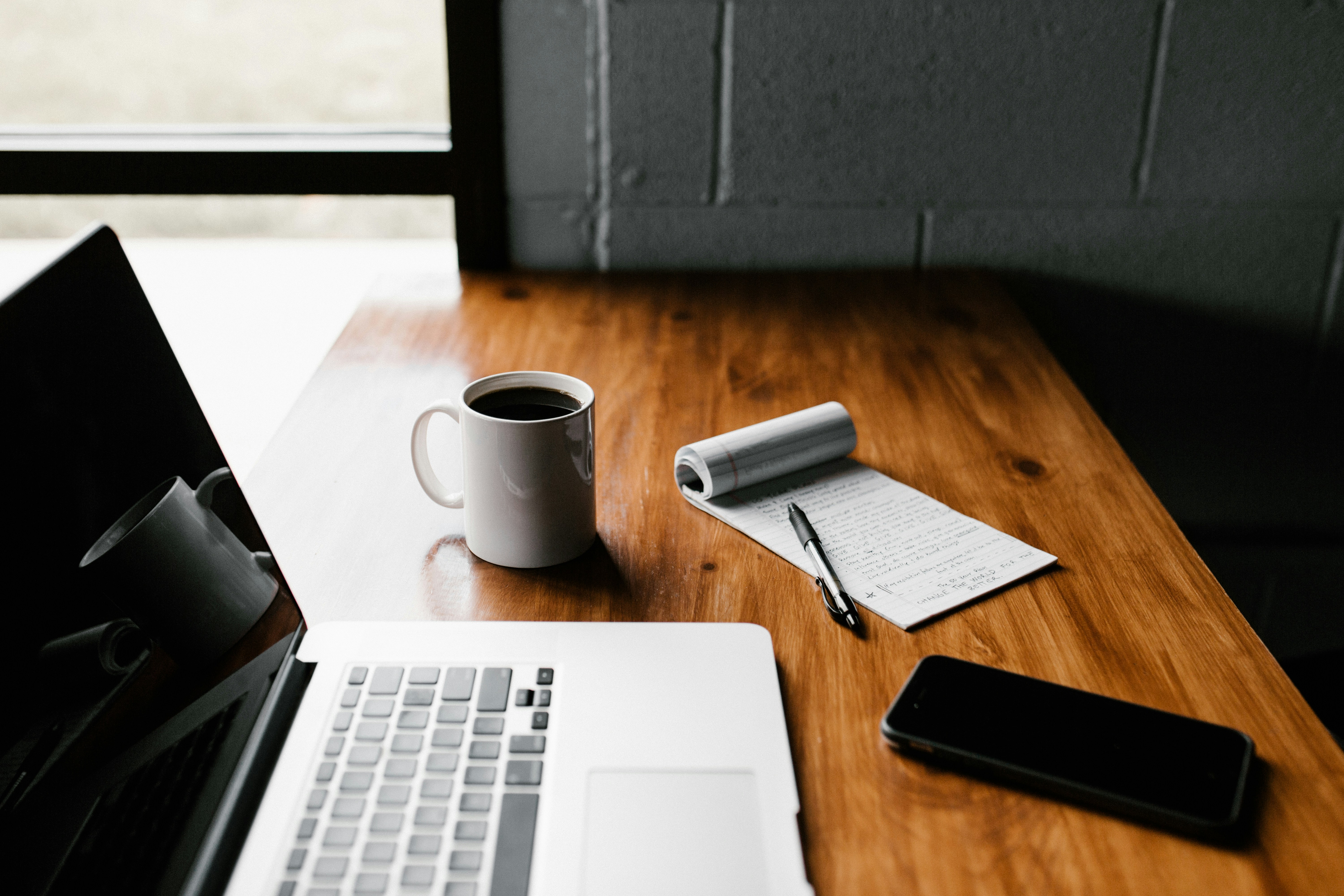 Stock photo of a laptop, coffee, pen, notepad and phone